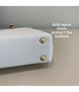 Detail of white lychee leather handbag bottom with gold protective metal studs