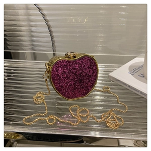 Macro detail of heart-shaped glitter evening bag with gold metal chain and clasp