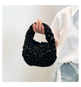 Close-up of black pleated ruffle satin handbag with elegant soft lace textures
