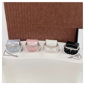 Close-up of pleated leather mini bags with pearl handles and metallic chain straps