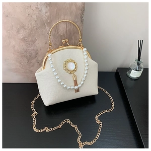 Detailed close-up of cream leather bag with pearl handle and vintage metal clasp closure