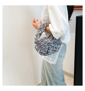 Detail of silver-grey pleated satin handbag with elegant ruffled texture and crescent shape