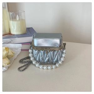 Detailed macro view of silver pleated mini bag with pearl handle and rhinestone diamond studs