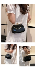 Detail of glossy black晚宴包 featuring golden ring handle and elegant floral clasp closure