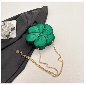 Detail of green acrylic flower bag with gold chain over a grey blazer and book