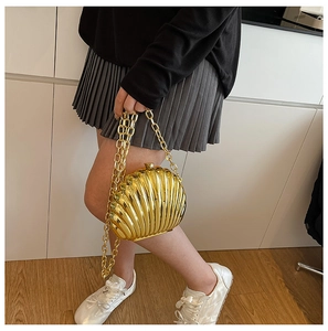 Macro shot of gold shell evening bag with metallic finish and thick chain strap