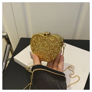 Detail of apple-shaped evening clutch bag with golden sequins and delicate chain strap