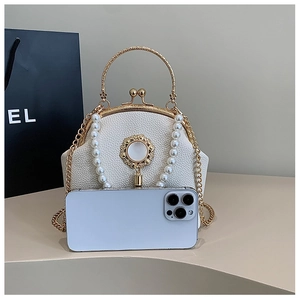 Detail of white lychee leather handbag with pearl embellishments and gold metal handle