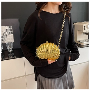 Close-up of golden shell-shaped evening clutch with glossy texture and thick chain strap