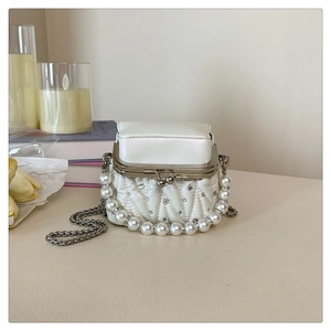 Detail of white quilted mini bag with pearl handle, crystals, and silver kiss-lock closure
