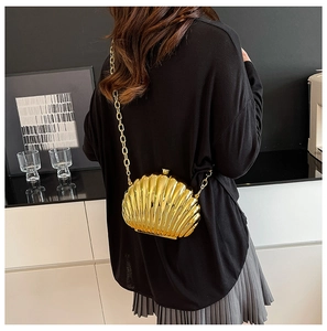 Chic gold shell clutch bag shown with chain strap on model for elegant party styling