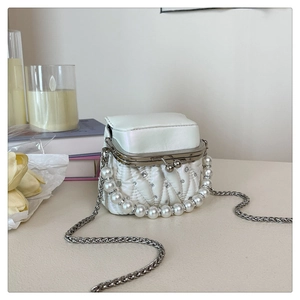 Detail of white pleated mini bag featuring pearl handle and sparkling rhinestone accents