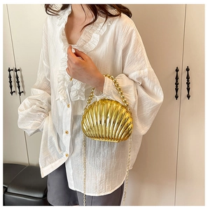 Detailed close-up of golden shell evening bag with beaded handle and metallic chain