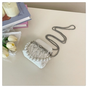 Detail of white quilted mini bag with pearl handle, crystals and silver chain strap