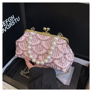 Dettaglio borsa a conchiglia con paillettes rosa, manico di perle e catena metallica