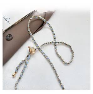 Detail of light blue leather-woven chain strap with adjustable golden diamond-patterned ball