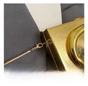 Close-up of golden textured handbag with metallic snake chain and lobster clasp connector