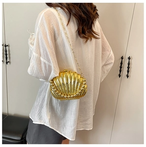 Detail of golden shell-shaped evening bag with pearl trim and delicate gold chain strap