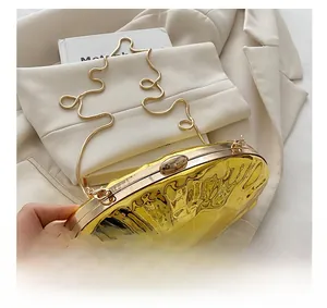 Detail of gold oval evening clutch showing wavy texture and delicate snake chain strap