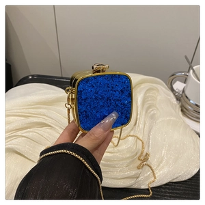 Close-up of blue glitter acrylic clutch bag with gold chain strap and metal lock