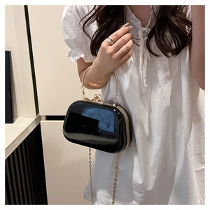 Detail of black patent leather evening bag with gold handle and sparkling rhinestone clasp