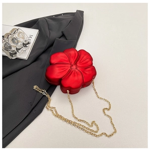 Detail of red flower evening bag with gold chain strap on grey blazer background