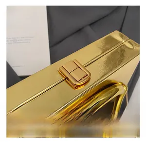 Close-up of golden metallic clutch showing textured surface and square push-lock clasp