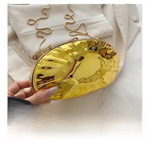 Detail showing the pleated golden shell-shaped metal clutch with a fine chain strap