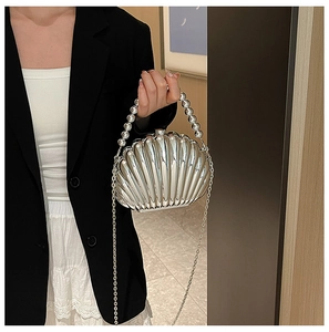 Silver shell clutch bag with pearl handle and metal chain shown on a model