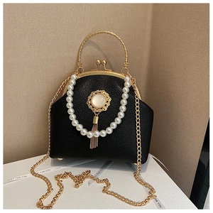 Detail of black lychee leather handbag with pearl chain and vintage gemstone brooch