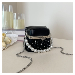 Detail of black pleated mini bag featuring pearl handle and silver ball clasp closure