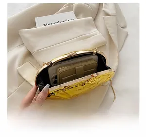 Close-up of golden metallic shell evening clutch showing interior storage for phone and wallet