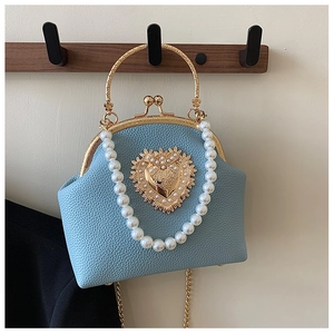 Detail of blue textured leather shell bag with gold heart ornament and pearl chain