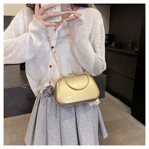 Close-up of golden evening clutch bag featuring a rhinestone clasp and fine chain strap