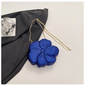 Detail of navy blue 3D flower acrylic bag with gold chain strap on minimalist background
