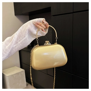 Detail of champagne gold evening clutch with jewel clasp, metal ring handle, and chain
