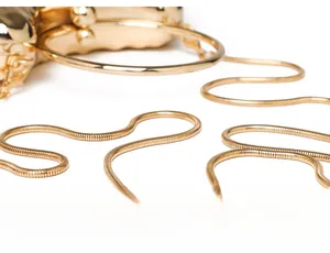Detail of evening clutch featuring golden metal handle and sleek snake chain strap