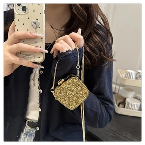 Detail of glitter acrylic clutch bag with gold chain strap and spherical clasp closure