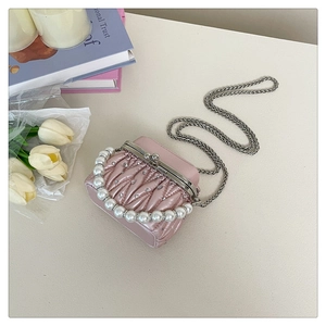 Detail of pink pleated mini bag with pearl handle and metal chain on elegant background