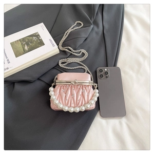 Mini pink pleated PU leather bag with large pearl handle and metal chain in macro view