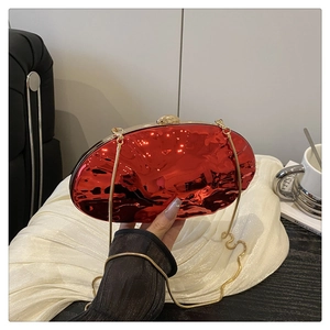Close-up of a glossy red metallic shell clutch with a gold chain strap for women