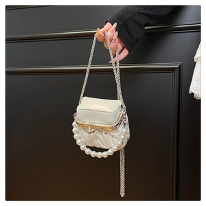 Detailed macro view of a white quilted mini bag with dense pearls and silver metal clasp