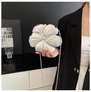 Detail of matte pearl white flower clutch bag with elegant silver metal chain strap