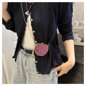 Close-up of pink glitter heart-shaped mini bag with gold chain strap worn on waist