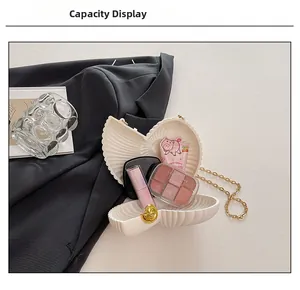 Macro view of shell-shaped acrylic clutch bag showing interior storage with gold chain