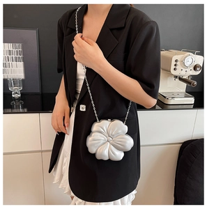 Silver flower evening bag with chain strap styled on model with black suit and white skirt