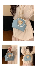 Detail of light blue shell bag featuring pearl handle and gold heart relief buckle