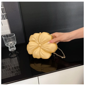 Detailed close-up of matte gold flower clutch bag with delicate metal chain strap