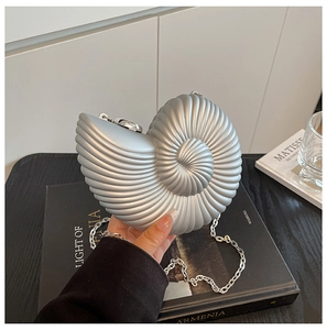 Detail of silver conch shell clutch showing metallic spiral texture and chain strap