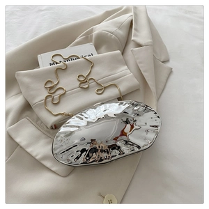 Detail of silver wavy acrylic clutch bag with metallic liquid effect and golden chain